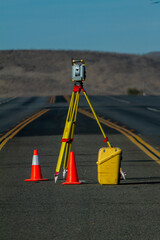 Land survey equipment set up on road with road becoming a hill in the background with traffic