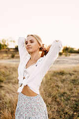 Fototapeta na wymiar Young blonde woman posing outdoors, in a field.