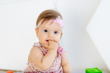 beautiful portrait of little baby girl sucking finger in red clothes