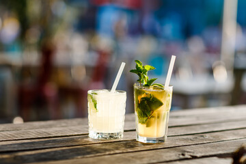 Two glasses fresh alcoholic cooling cocktail in summer on the terrace of a cafe. A refreshing mojito with ice, mint and lime best idea to cool off in the hot summer.