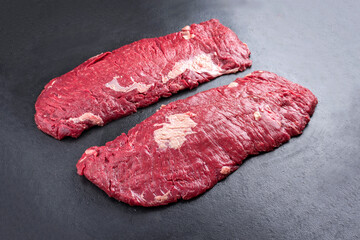 Raw wagyu bavette beef steak offered as close-up on rustic black board with copy space