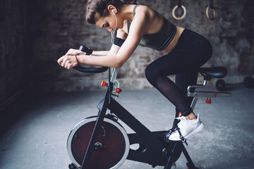 Fit woman on bicycle doing spinning at gym