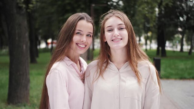 Pretty smiling girls students look at camera and smiling. Close up portrait of happy beautiful sisters.