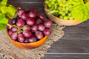 clusters of pink and green grapes in wooden bowls close-up. background with green and pink fresh grapes and vine.