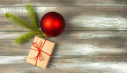 Christmas greeting card with fir branch and gift on wooden background.