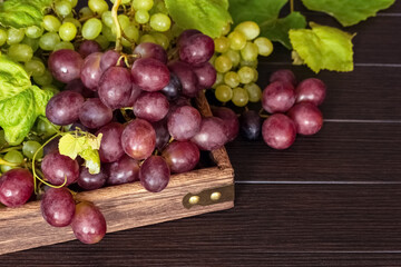fresh green and pink grapes close-up in a wooden box on a wooden background. background with green and red grapes