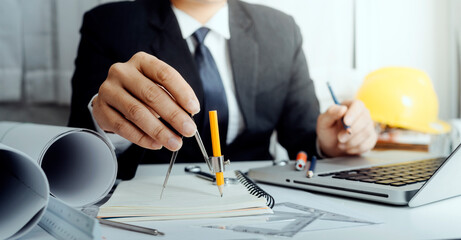 Two colleagues discussing data working and tablet, laptop with on on architectural project at construction site at desk in office