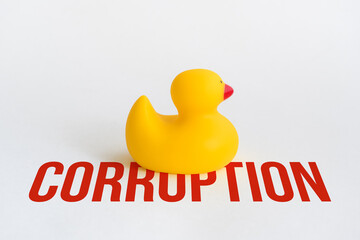 Toy yellow rubber duck on word corruption. Opposition symbol and political struggle. Minimalistic concept on white background