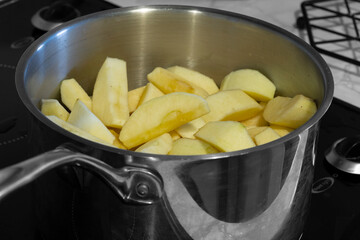 Apples stewing in a saucepan on a hob stove.  Selective colour