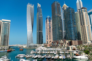 Fototapeta na wymiar Stunning panoramic view of Dubai Marina skyline, yachts and boats moored at the pier on a bright sunny day. Dubai, United Arab Emirates.