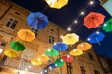 view of evening city street decorated with colorful umbrellas