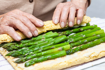 Close up of a senior woman hands rolling a just baked sponge cake