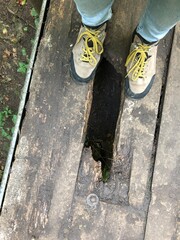 Wanderschuhe auf alten Bohlen mit Loch, Abgrund 