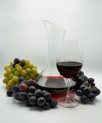 Decantador y copa rodeados de uvas tintas y blancas