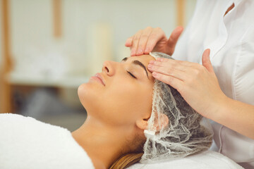 Fototapeta na wymiar Woman getting procedure of relaxing facial massage treatment from cosmetologist