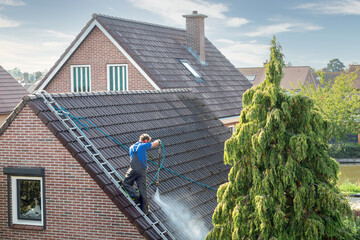 Fototapeta Cleaner with pressure washer at roof house cleaning roof tiles obraz