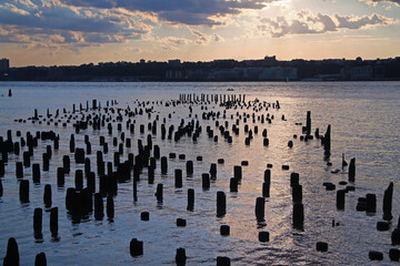 The sunset and the clouds among the stakes in the river