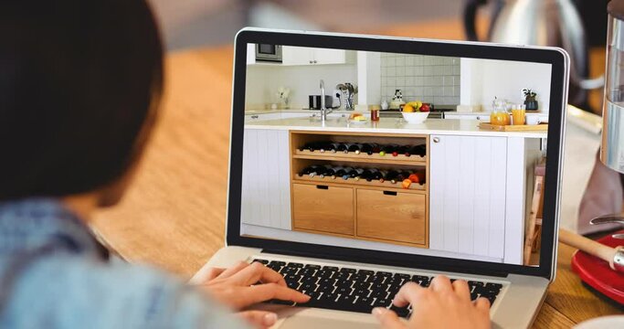 Woman using laptop with modern kitchen interiors displayed on screen