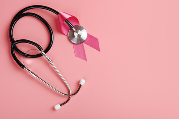 Pink ribbon and stethoscope on pink background. Breast cancer awareness concept, copy space for text, flat lay 