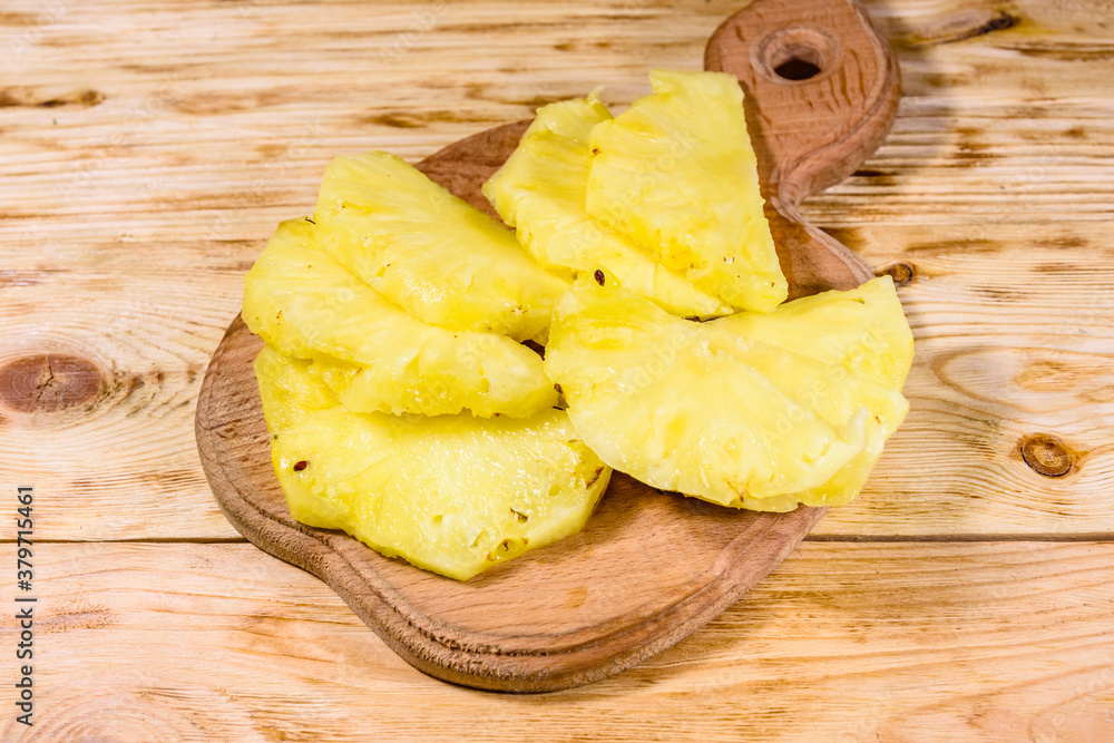 Wall mural Cutting board with sliced pineapple on wooden table