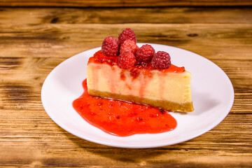 White plate with cheesecake New York and raspberries on wooden table