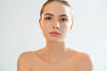 Beauty care. Aesthetic cosmetology. Portrait of sensual woman with perfect face skin nude makeup bare shoulders looking at camera isolated on light white copy space background. Anti-aging therapy.