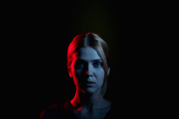 Female silhouette portrait. Feeling helpless. Worried woman in neon light glow looking at camera isolated on black cope space. Psychology support. Domestic violence. Stuck problem. Toxic relationship