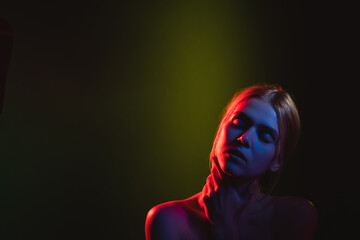 Female silhouette. Neon light portrait. Relaxed woman bare shoulder in green red glow closing eyes...