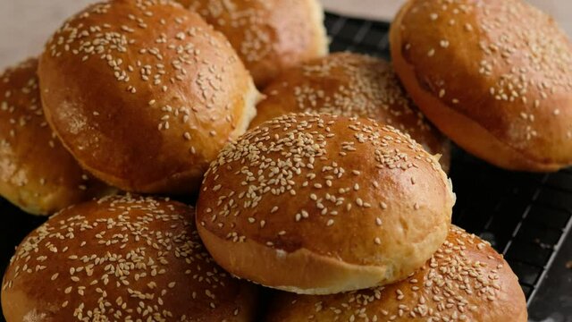 Baker woman cooking buns for burgers. Hot buns from the oven. Handmade bread Making. Preparing dough for baking buns. At the bakery, preparing dough to be cook buns, bread. Beautiful background.