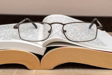 Reading glasses on a stack of books close up