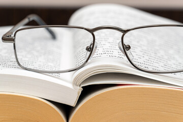 Reading glasses on a stack of books close up