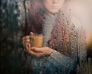 the girl looks at the rain through the window