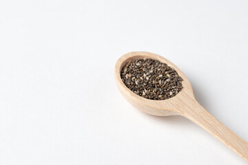 Superfood concept with chia seeds in wooden spoon on white background.