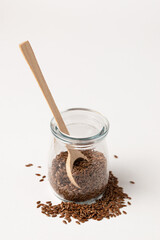 Macro photo of raw flax seeds in glass jar on white background for Superfood and diet product concept
