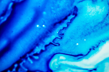 Blue refill ink spilled onto the white sink and the ink blended into abstract drops and patterns.