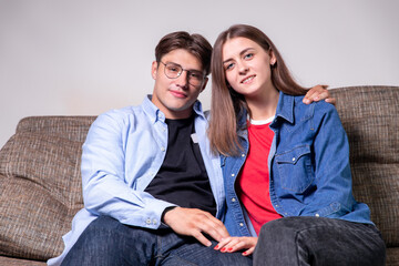 Young couple relaxing on the sofa smiling at the camera at home in the living room
