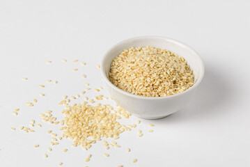 Raw sesame seeds in ceramic bowl on white background for Superfood and diet product concept, close up