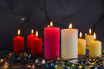 A thin wax candle with a small lit flame with a background. Candles on an old table. Beautiful background. Religious concept.