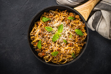 Pasta Bolognese in the skillet at black table.