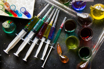 Colorful medical needle and lab glassware with chemical drugs and vaccine