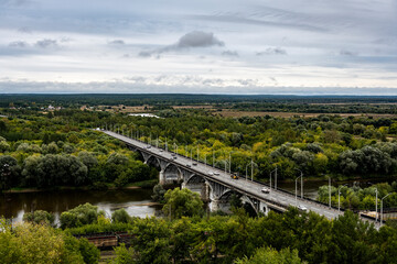 Obraz premium road across the river against the background of a green forest from the observation deck