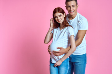 pregnant mom and happy father on pink background Young family waiting for baby