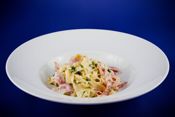Carbonara pasta with bacon and basil on a plate.