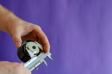 Vernier caliper and timing belt tensioner in hand on blue background.