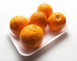 Group of oranges on a polystyrene tray on white background, supermarket presentation, high angle camera shoot, diagonal arrangement