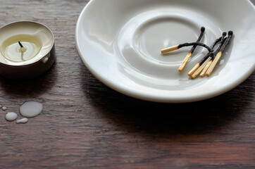 A darkened small candle on a wooden table.