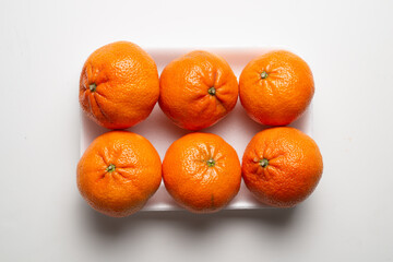 Group of tangerines on a polystyrene tray on white background, supermarket presentation, top down camera view, lay flat presentation horizontal arrangement