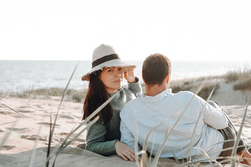 sea tour. a couple of girl and guy are lying on the sand. hat, reeds .

