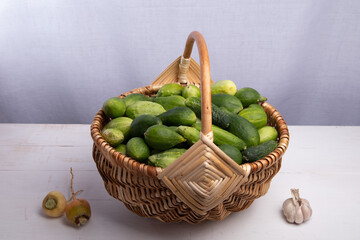 wicker basket with fresh cucumbers on a wooden background