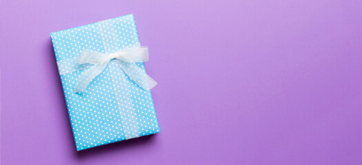 wrapped Christmas or other holiday handmade present in paper with white ribbon on purple...
